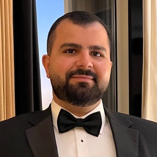 Khaled Shoukry, smiling, in a black tuxedo and bow tie