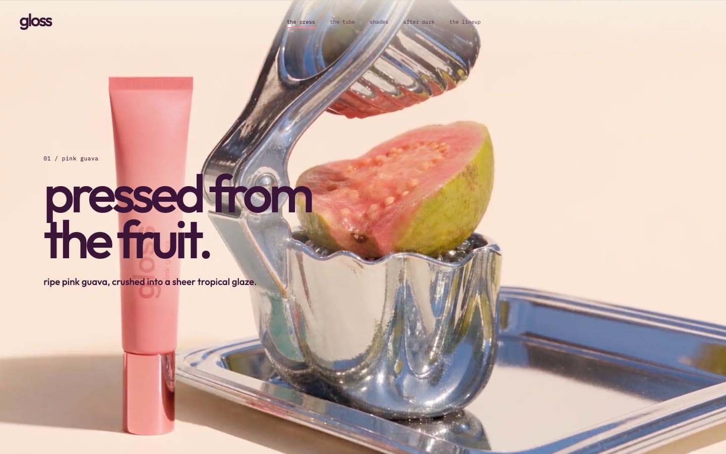 The gloss campaign site on desktop: a halved pink guava in a chrome press beside a pink gloss tube, under the headline 'pressed from the fruit.'